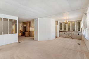 Unfurnished room featuring a chandelier and light colored carpet