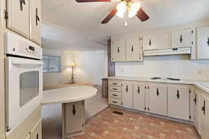 Kitchen featuring light countertops, white appliances, and cream cabinets