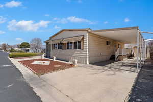 View of front of house with concrete driveway, an attached carport, and an outdoor structure
