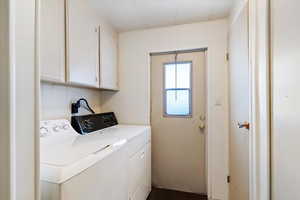 Laundry area with separate washer and dryer, cabinet space, and wooden walls