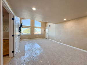 Unfurnished living room with light colored carpet, a textured ceiling, and recessed lighting
