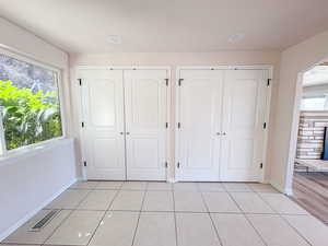 Unfurnished bedroom featuring light tile patterned floors and multiple closets