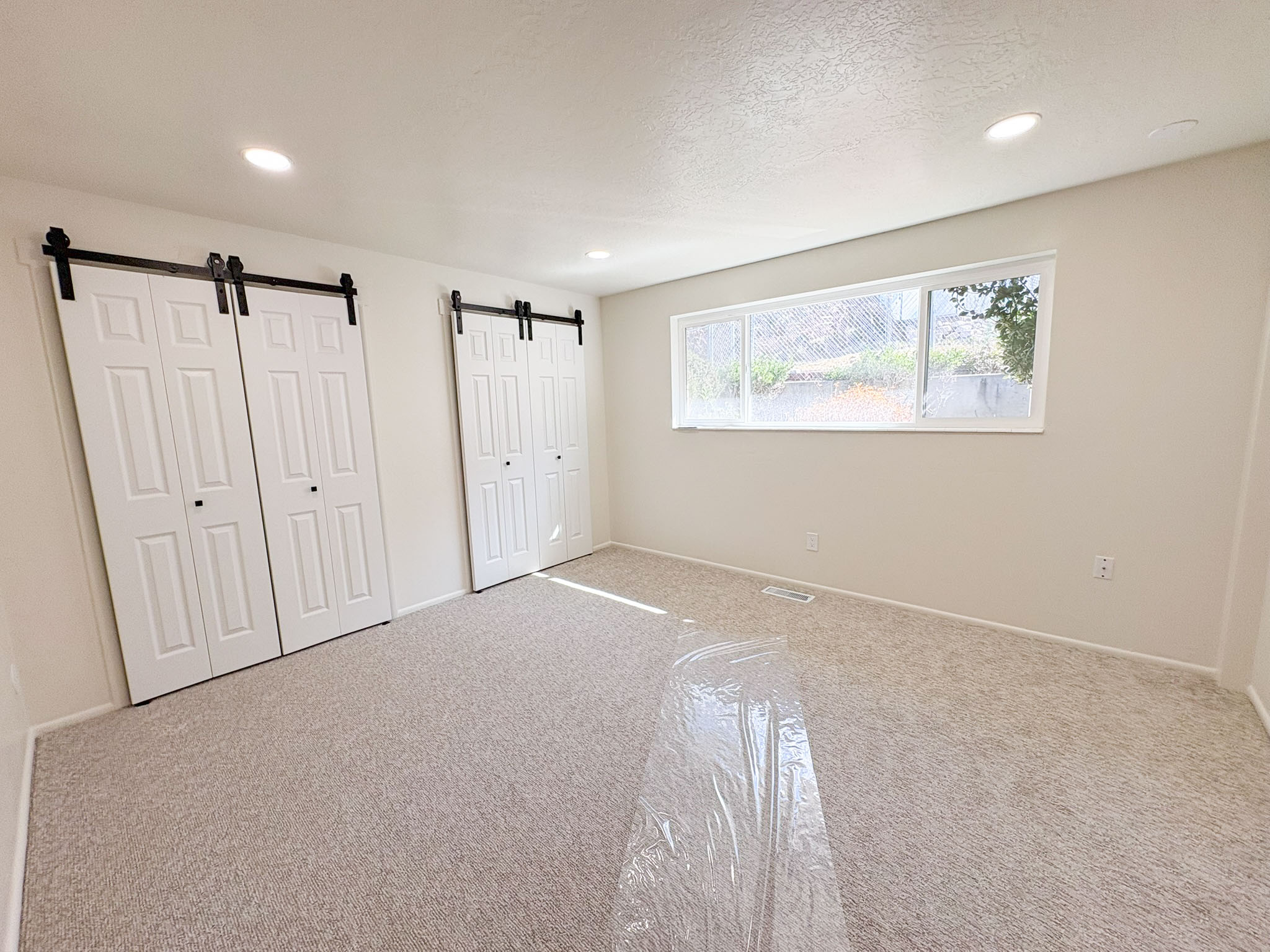 Unfurnished bedroom with a barn door, carpet floors, two closets, recessed lighting, and a textured ceiling
