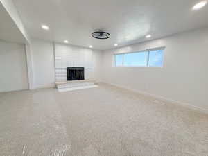 Unfurnished living room with carpet floors, a brick fireplace, and recessed lighting