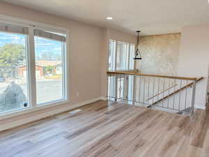 Unfurnished living room featuring light wood-style flooring, a textured ceiling, and recessed lighting