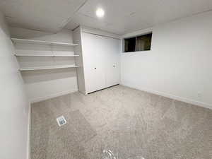 Unfurnished bedroom with a drop ceiling, light carpet, and a closet