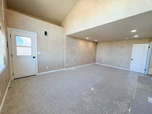 Carpeted empty room featuring lofted ceiling and recessed lighting