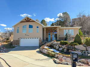 View of front of property featuring stone siding, covered porch, a garage, and driveway