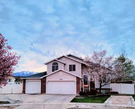 View of front of property with brick siding, driveway, a garage, and a mountain view