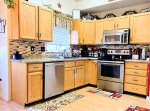 Kitchen with light wood finish cabinetry, stainless steel appliances, light countertops, and light wood finished floors