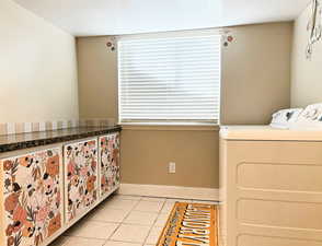 Laundry room with light tile patterned floors, a textured ceiling, and separate washer and dryer