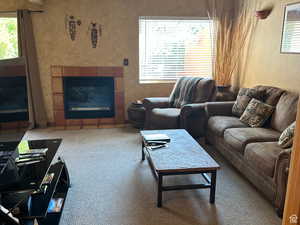Carpeted living area featuring a tiled fireplace and a textured wall