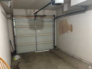 Garage featuring a garage door opener and baseboards