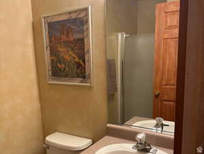 Bathroom featuring a textured wall, vanity, and a shower with shower door