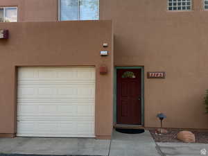Doorway to property featuring stucco siding and a garage