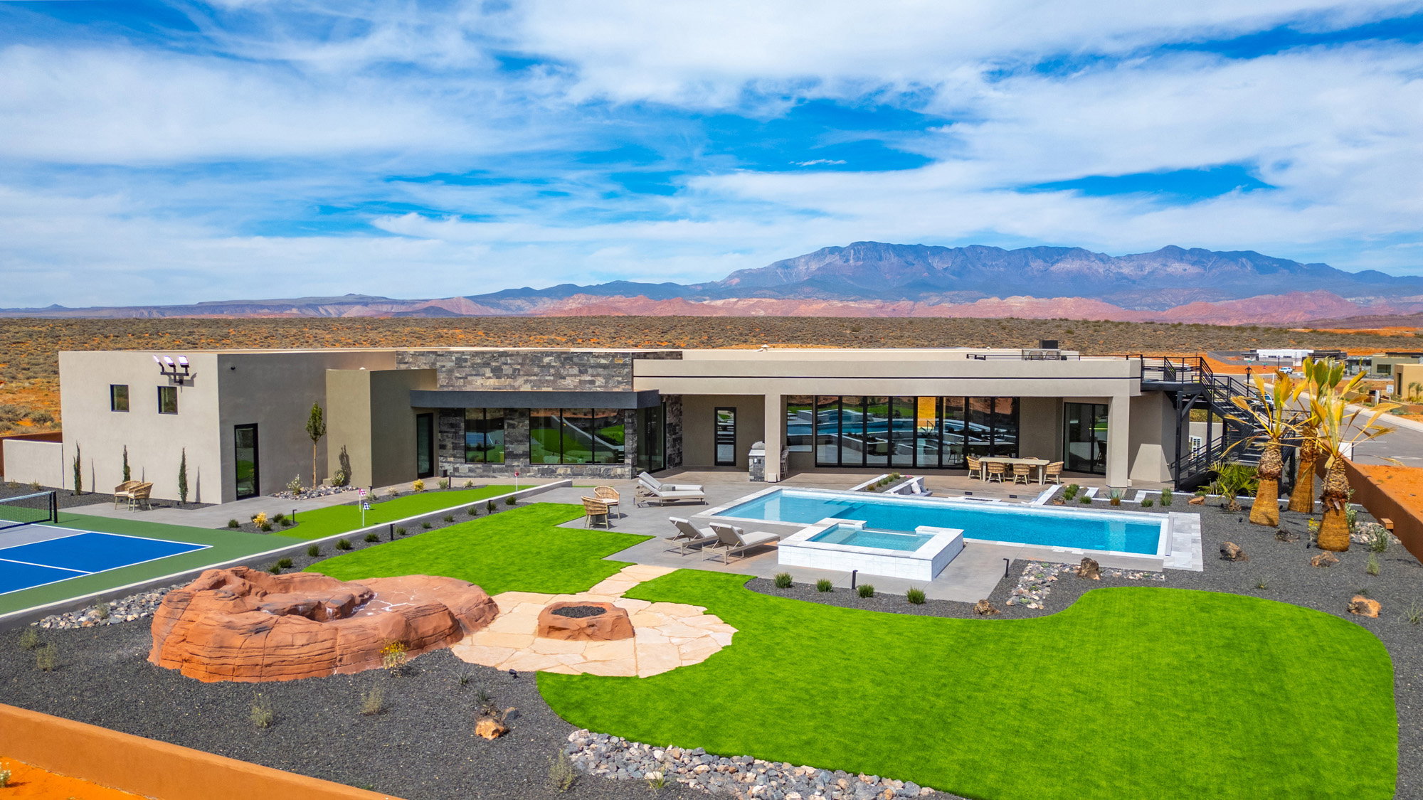 Back of house with an outdoor fire pit, a mountain view, a patio area, stone siding, and stucco siding