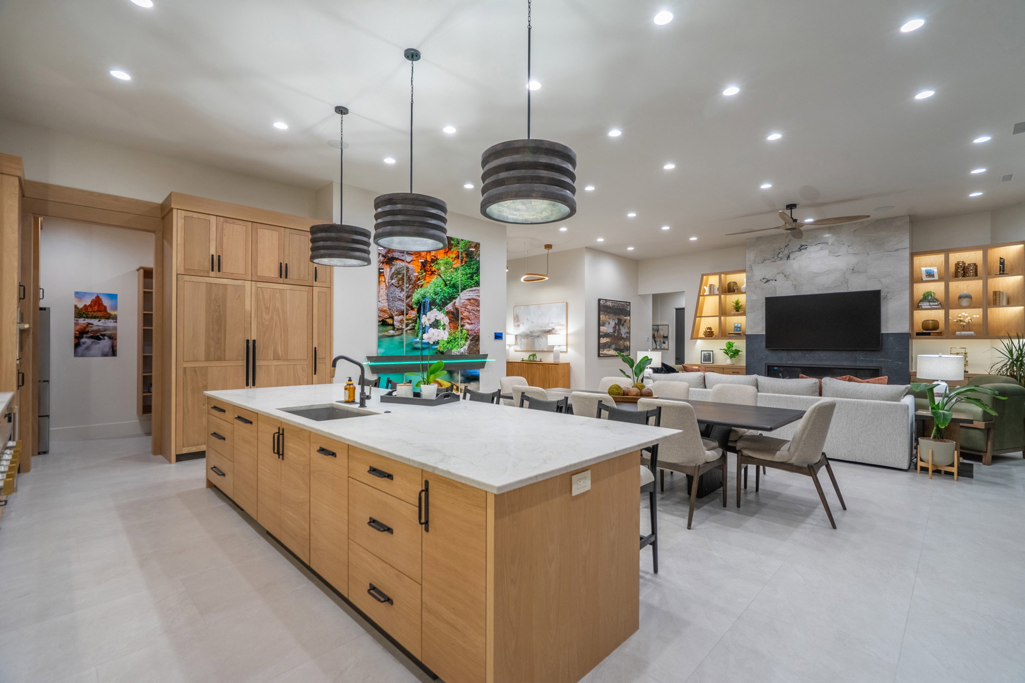 Kitchen featuring light stone countertops, a large island, light wood finish cabinetry, open floor plan, and hanging light fixtures