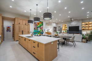 Kitchen featuring light stone countertops, a large island, light wood finish cabinetry, open floor plan, and hanging light fixtures