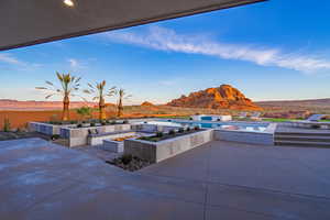 View of patio / terrace with an outdoor fire pit, a hot tub, a mountain view, and an outdoor pool