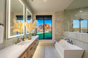 Full bath with vanity, a freestanding bath, and tile walls