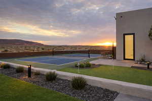 View of tennis court with a mountain view and a patio