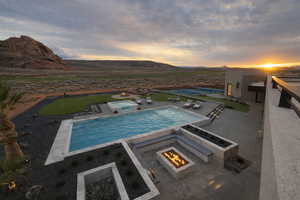 Pool at dusk featuring an in-ground hot tub, an outdoor pool, a patio, and a mountain view