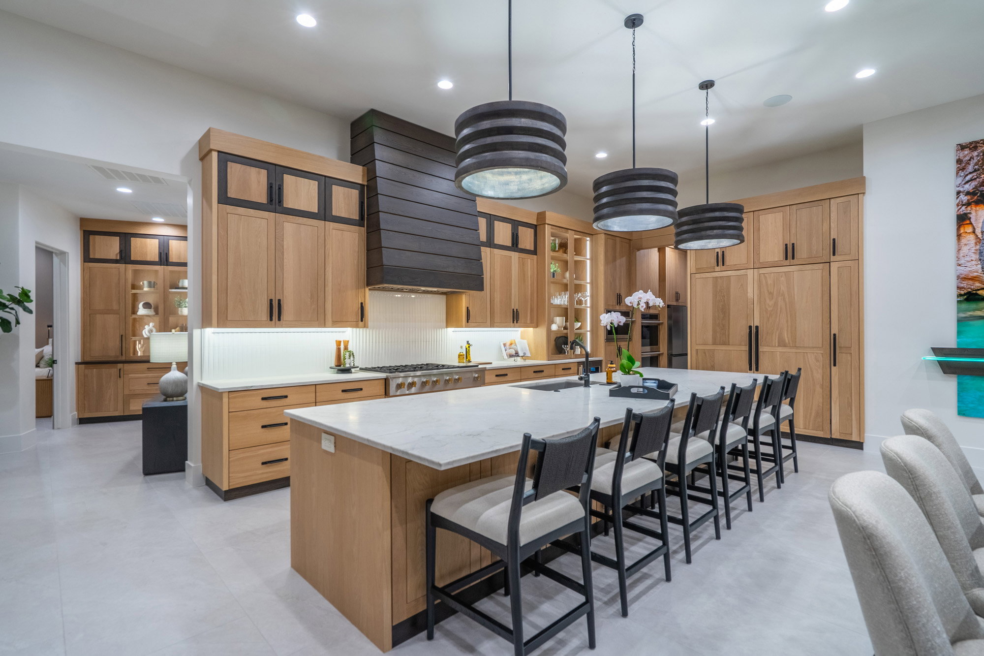 Kitchen with a breakfast bar, a spacious island, light stone countertops, and glass fronted cabinets