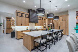 Kitchen with a breakfast bar, a spacious island, light stone countertops, and glass fronted cabinets