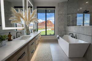 Bathroom with double vanity, a freestanding bath, a mountain view, and tile walls