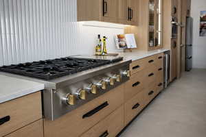 Kitchen with stainless steel appliances, light stone countertops, glass fronted cabinets, modern cabinets, and wine cooler