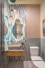 Half bath featuring vanity, tile walls, and a wainscoted wall