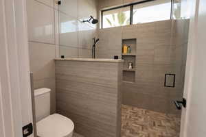 Full bathroom featuring a shower stall and toilet