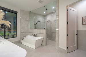 Full bathroom with tile walls, walk in shower, a freestanding tub, and vanity