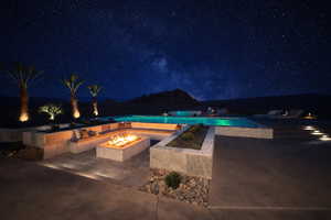Pool at twilight featuring a fire pit, an outdoor pool, a patio, and an in-ground hot tub