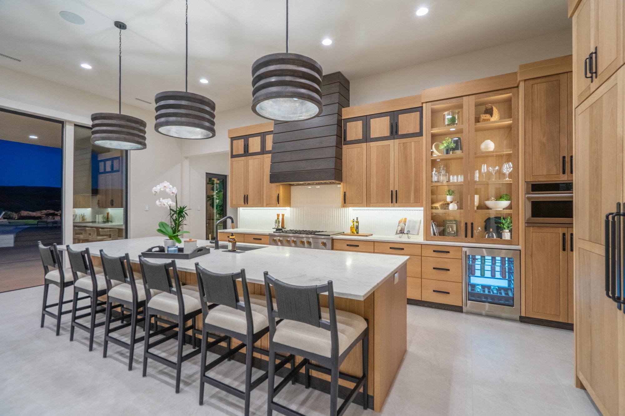 Kitchen featuring a kitchen bar, beverage cooler, a large island, hanging light fixtures, and light stone counters