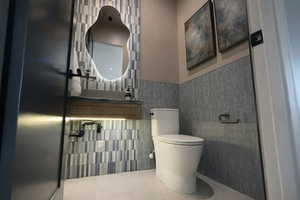 Half bathroom with toilet and a wainscoted wall