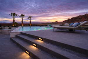 Pool at dusk featuring a mountain view, an outdoor pool, and a patio