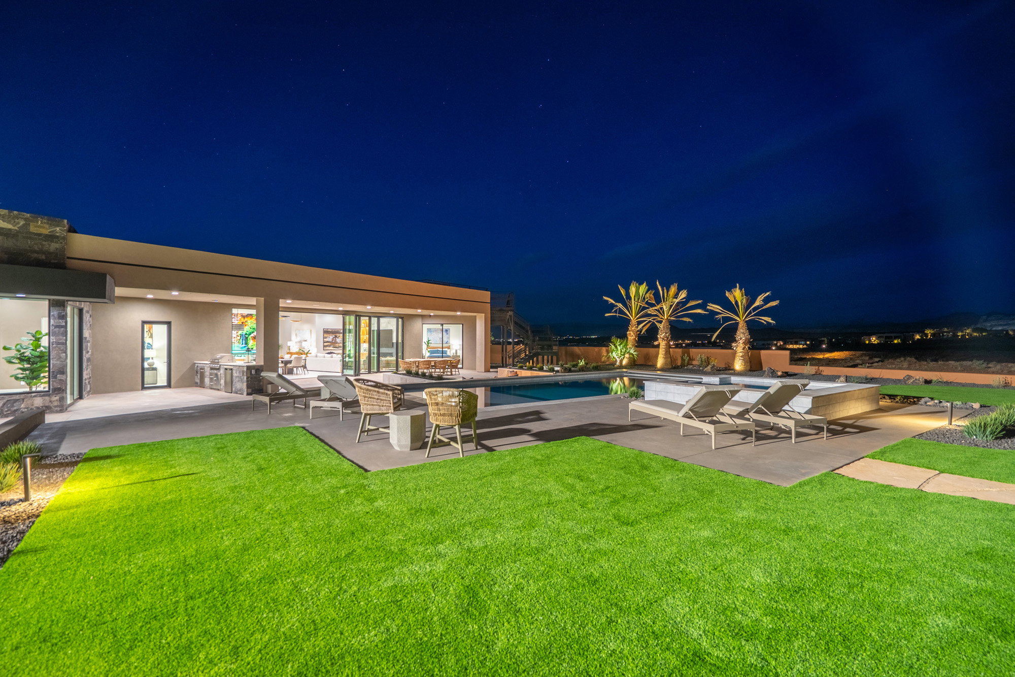 Pool at night with a patio area, an outdoor pool, and a lawn