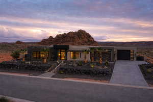 Contemporary home with stone siding, an attached garage, driveway, and a mountain view