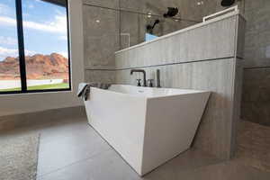 Full bath with walk in shower, a freestanding tub, concrete flooring, tile walls, and a mountain view