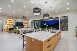 Kitchen with light stone counters, open floor plan, a spacious island, and a breakfast bar area