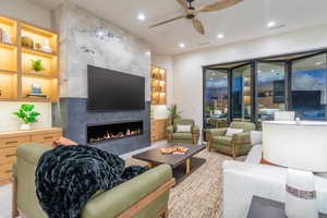 Living area with a ceiling fan, a high end fireplace, built in shelves, and recessed lighting