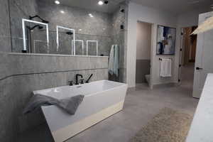 Full bathroom with finished concrete flooring, a freestanding tub, and walk in shower