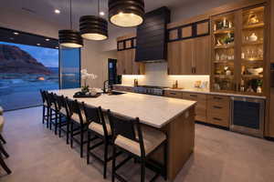 Kitchen featuring a kitchen breakfast bar, a spacious island, wine cooler, light stone countertops, and glass insert cabinets