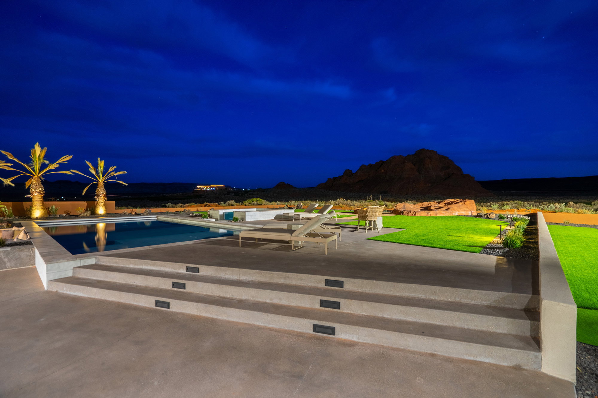 Pool at night with a patio, an outdoor pool, and a lawn