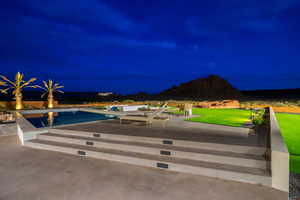 Pool at night with a patio, an outdoor pool, and a lawn
