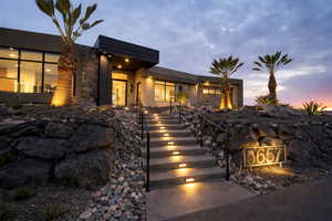 View of front facade featuring stucco siding, stone siding, and a patio