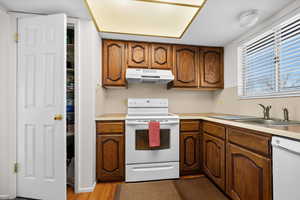 Kitchen with white appliances, light countertops, wood finish cabinets, and light wood-style flooring