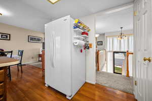 Kitchen featuring freestanding refrigerator, dark wood-style flooring, and hanging lights