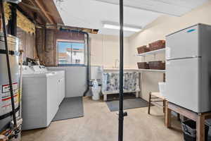 Laundry area featuring concrete flooring, secured water heater, and separate washer and dryer